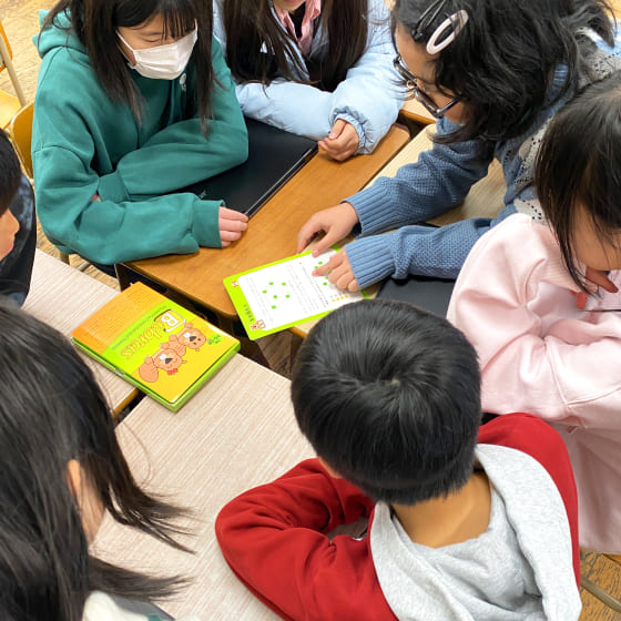 写真:カードを真ん中に7人の児童が集まっている